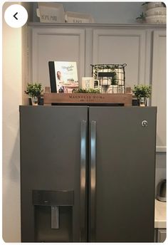 a refrigerator with the door open and some plants on top, in front of white cabinets