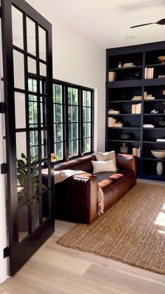 a living room filled with furniture and bookshelves next to a large open window