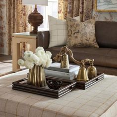 a living room filled with furniture and flowers on top of a coffee table in front of a window