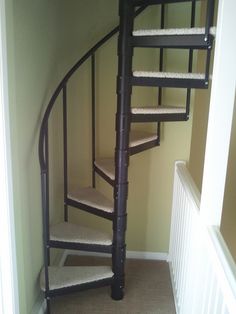 there is a spiral staircase in the corner of this room with carpet on the floor