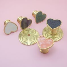 four heart shaped brooches sitting on top of a pink surface next to each other