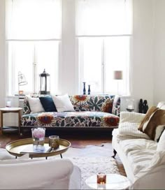 a living room filled with lots of furniture next to two windows and a rug on the floor