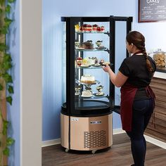 a woman standing in front of a display case filled with food