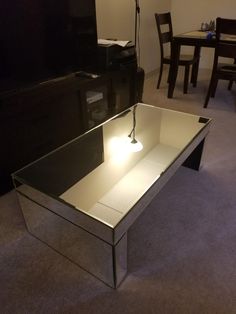 a glass table with a light on it in the middle of a room next to a tv