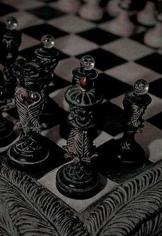 black and white chess pieces on a checkerboard board with an intricate design in the middle