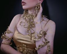 a woman wearing gold jewelry with her hands on her face