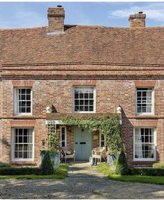 an old brick house with ivy growing on the front door and windows, surrounded by hedges