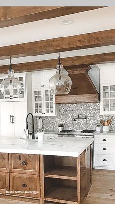 a large kitchen with white cabinets and wooden flooring is pictured in this image, there are two pendant lights hanging from the ceiling