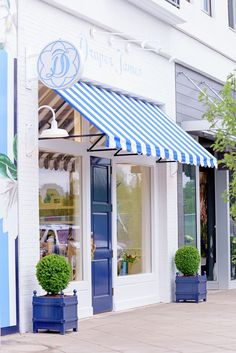 two blue planters are sitting in front of a storefront with striped awnings