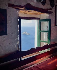 an open window with a view of the ocean and land in the distance from a bed