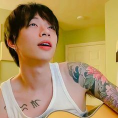 a man with tattoos on his arm holding a guitar