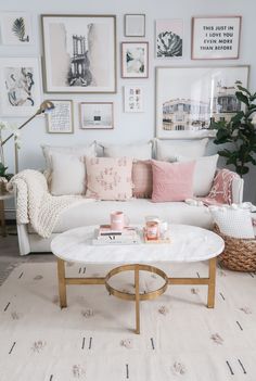 a living room filled with white furniture and pictures on the wall above it's coffee table