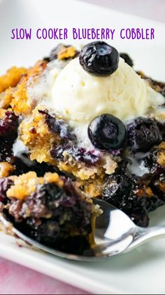 a white plate topped with blueberry cobbler next to a fork and ice cream