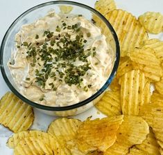 a glass bowl filled with dip surrounded by chips