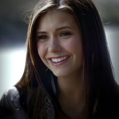 a close up of a person with a smile on their face and long dark hair