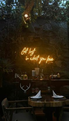 the neon sign above the table says, get lost in what you love