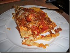 a white plate topped with lasagna covered in sauce and cheese next to a fork