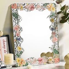 there is a mirror with flowers on it next to a vase and candles in front of the mirror