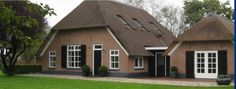 the house is made of brick and has black shutters on the front door, windows, and two dormers