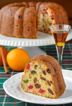 a bundt cake on a plate with an orange in the background and a glass of wine