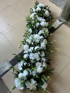 white flowers on the ground next to a metal pole with an elevator in the background