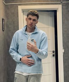 a man taking a selfie in front of a mirror with his hand on his hip