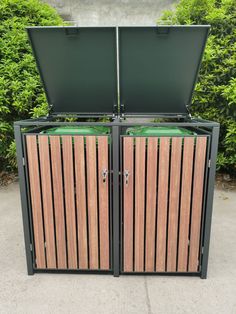 two wooden trash cans sitting next to each other in front of some bushes and shrubbery