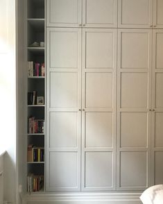 an empty room with white cupboards and bookshelves