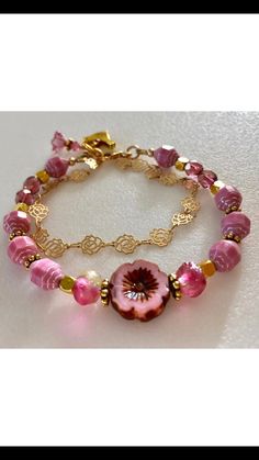 Lovely double strand beaded Premium Czech glass flower bracelet featuring Picasso pink turbine beads, Czech pink sea glass, pink cherub fire polished crystals, and single 15 mm pink Picasso pansy flower. All accented with antique gold plated daisies and shiny cubes. Satin Hamilton rose chain adds the perfect delicate second strand. Premium gold electroplated brass chain in satin finish with intricate rose flower pattern. Bracelet is beaded on professional Soft Flex beading wire with high quality Pink Beaded Czech Glass Jewelry, Pink Faceted Beaded Bracelets As A Gift, Pink Faceted Beaded Bracelet As A Gift, Adjustable Pink Bracelets, Adjustable Pink Single Strand Beaded Bracelets, Pink Faceted Bracelet Jewelry, Adjustable Pink Single Strand Beaded Bracelet, Pink Faceted Jewelry Bracelet, Adjustable Single Strand Pink Beaded Bracelet