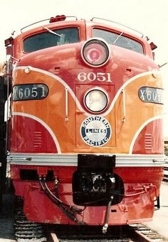 an orange and red train engine sitting on the tracks