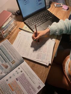 a person sitting at a desk with a laptop and papers on the table next to them