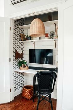 a black chair sitting in front of a tv on top of a white shelf next to a wooden floor