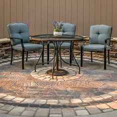 three chairs sitting around a small table in the middle of a circular stone patio area