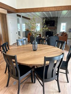 a dining room table with chairs and a vase filled with flowers on top of it