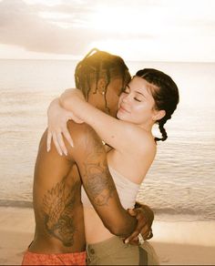 two people hugging each other on the beach