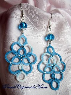 blue and white crochet earrings with crystal beads on top of a lace cloth