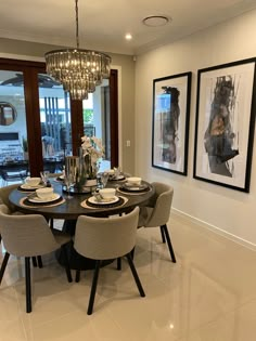 the dining room table is set with place settings for six people, and there are pictures on the wall behind it