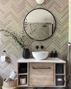 a white sink sitting under a round mirror next to a wooden cabinet in a bathroom