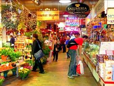 people are shopping in an open market with lots of plants and flowers on the shelves