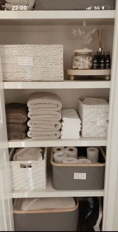 an organized closet with baskets, towels and other items in it's shelving