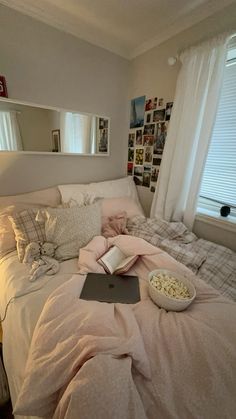 a laptop computer sitting on top of a bed in a bedroom next to a window