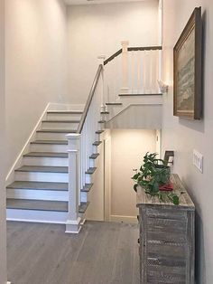 a white staircase leading up to the second floor in a home with hardwood floors and gray stairs