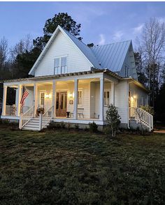 a small white house with porches and lights on