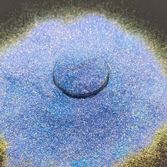 a circular object is shown in the middle of blue and yellow glitters on a black surface