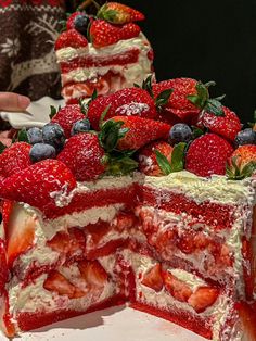 a cake with strawberries and blueberries on top is cut in half to show the layers