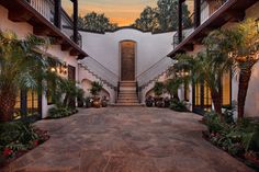 an outdoor courtyard with steps leading up to the front door and palm trees on either side