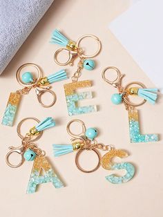 six key chains with letters and tassels on them