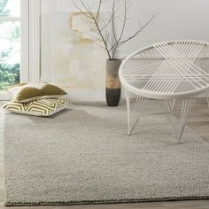 a white chair sitting on top of a wooden floor next to a vase filled with flowers