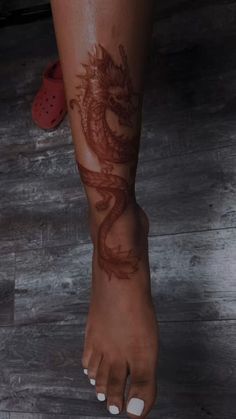 a woman's foot with a dragon tattoo on it