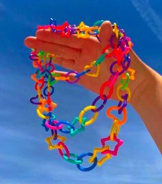 a hand holding up a multicolored chain with stars and hearts attached to it